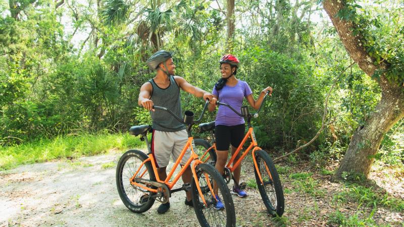 Two people riding bicycles at Anastasia State Park.