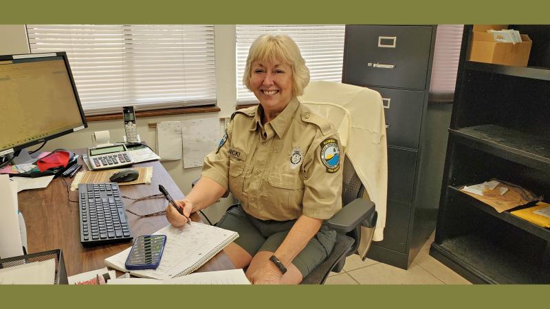 Person in uniform with blonde hair sitting at a desk.